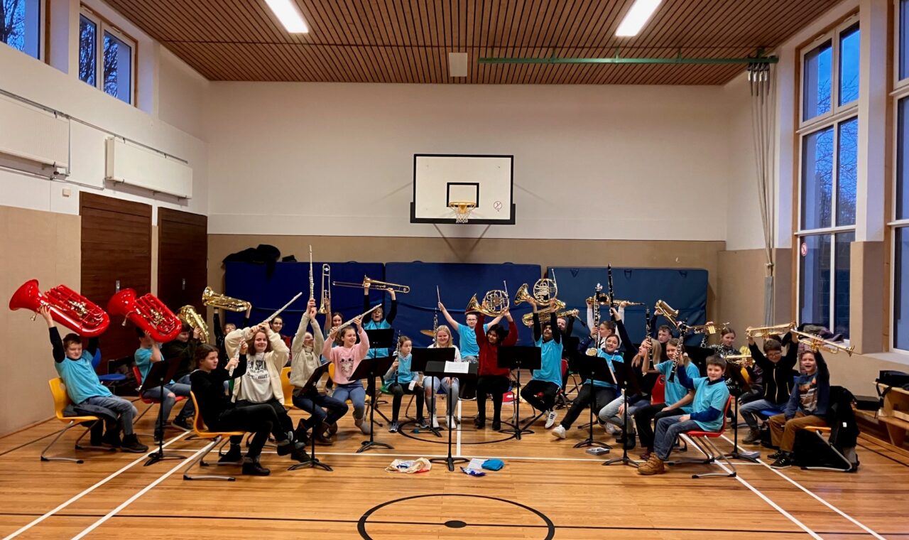 Schüler spielen Musikinstrumente in einer Turnhalle.
