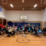 Schüler spielen Musikinstrumente in einer Turnhalle.