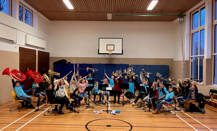 Schüler spielen Musikinstrumente in einer Turnhalle.
