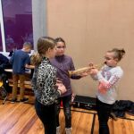 Kinder stehen in einer Klasse und zeigen Musikinstrumente.