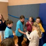 Kinder in blauen T-Shirts stehen in einer Gruppe und tauschen Instrumente aus.