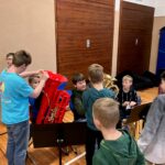 Kinder üben gemeinsam mit verschiedenen Blasinstrumenten in einem Musikraum.