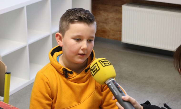 Ein Junge in einem gelben Hoodie spricht mit einer Person, die ein Mikrofon hält.