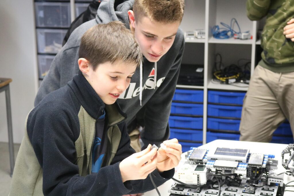 Zwei Schüler arbeiten gemeinsam an einem Tisch mit technischen Bauteilen.