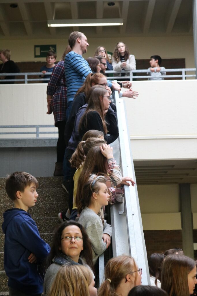 Gruppierung von Schülern und Lehrern in einem Treppenhaus, beobachtende Haltung.