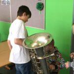 Kinder spielen mit einer Tuba in einem Klassenraum.