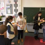 Schülerinnen und Schüler mit Instrumenten in einem Klassenraum.