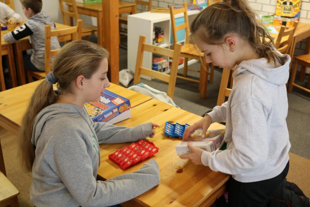 Zwei Mädchen spielen an einem Tisch mit roten und blauen Spielsteinen.