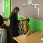 Schülerin zeigt einem Jungen eine Tuba im Klassenraum.