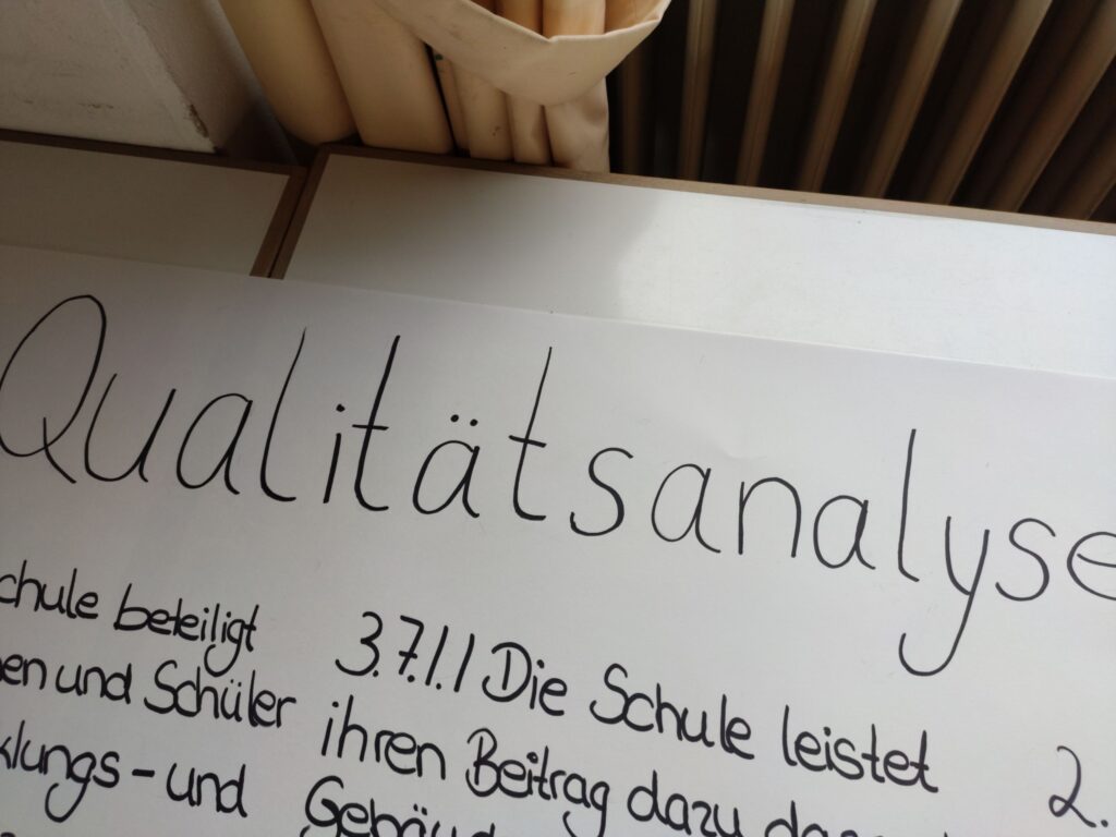 Ein Plakat mit der Überschrift "Qualitätsanalyse" und Textnotizen.