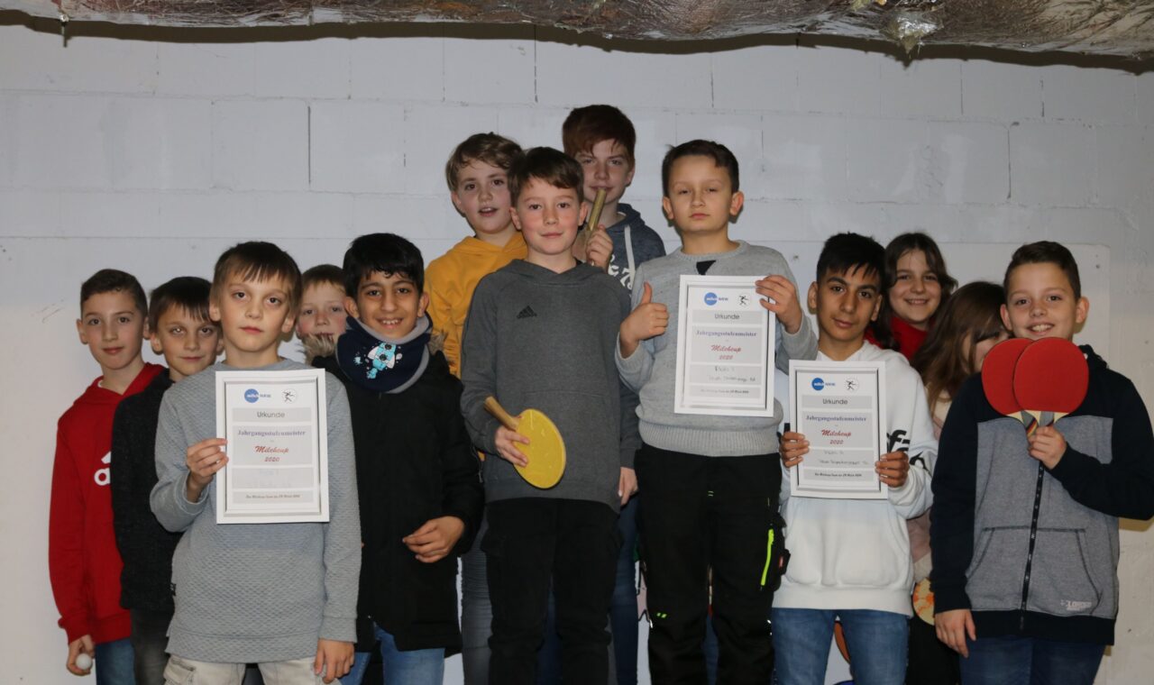 Gruppe von Schülern mit Urkunden und Tischtennisschlägern in einem Raum.