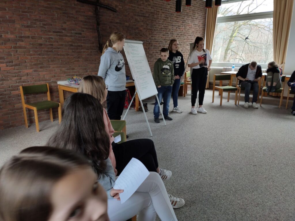 Gruppendiskussion mit Jugendlichen in einem Sitzungssaal. Moderatoren präsentieren.