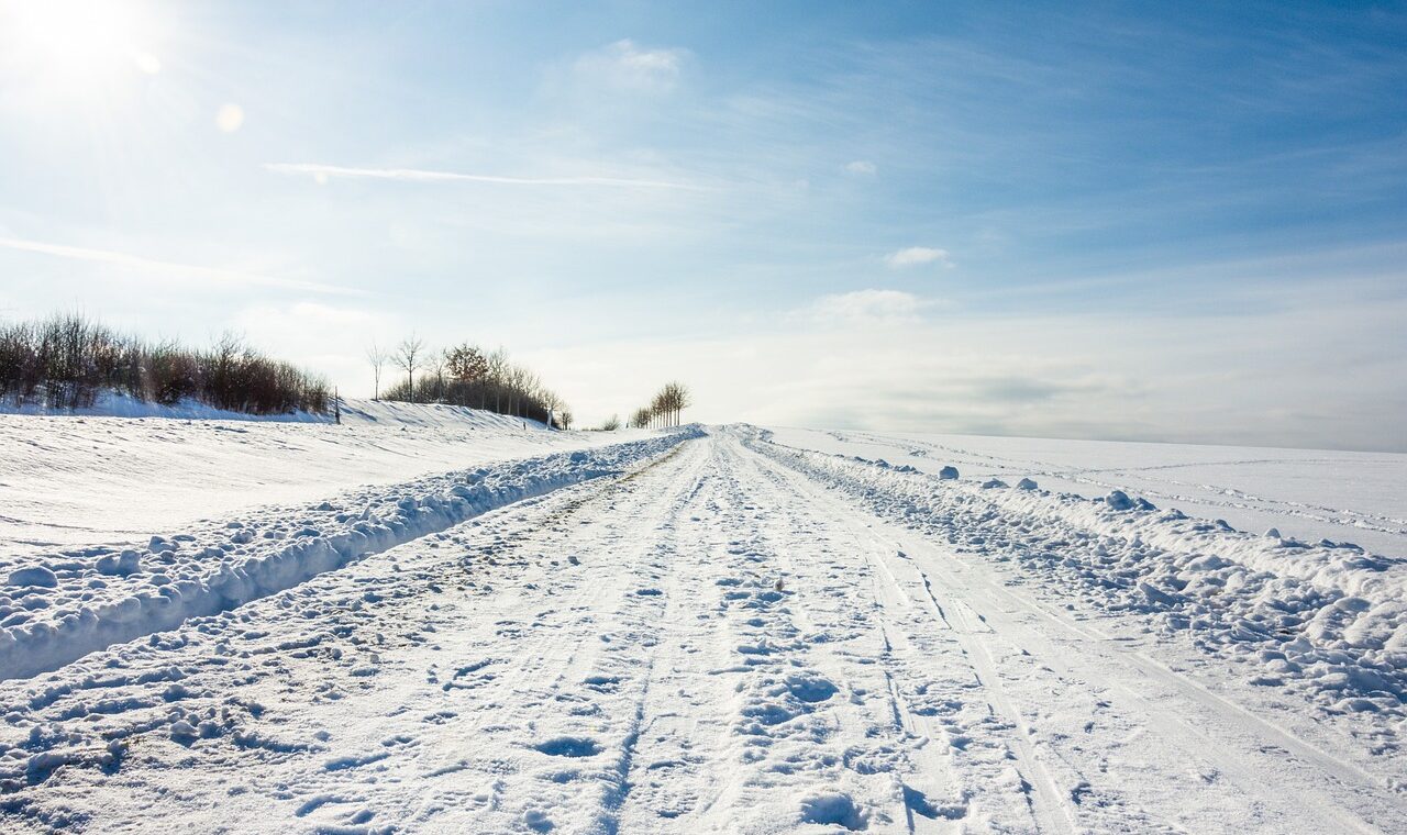 Schneebedeckte Straße unter blauem Himmel. Eindeutige Fußabdrücke im Schnee.
