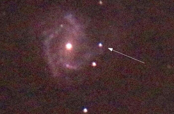 Supernova in einer Spiralgalaxie mit sichtbaren Sternen im Hintergrund.