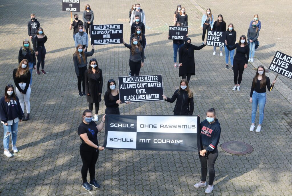 Schüler*innen halten Plakate für Black Lives Matter und gegen Rassismus.