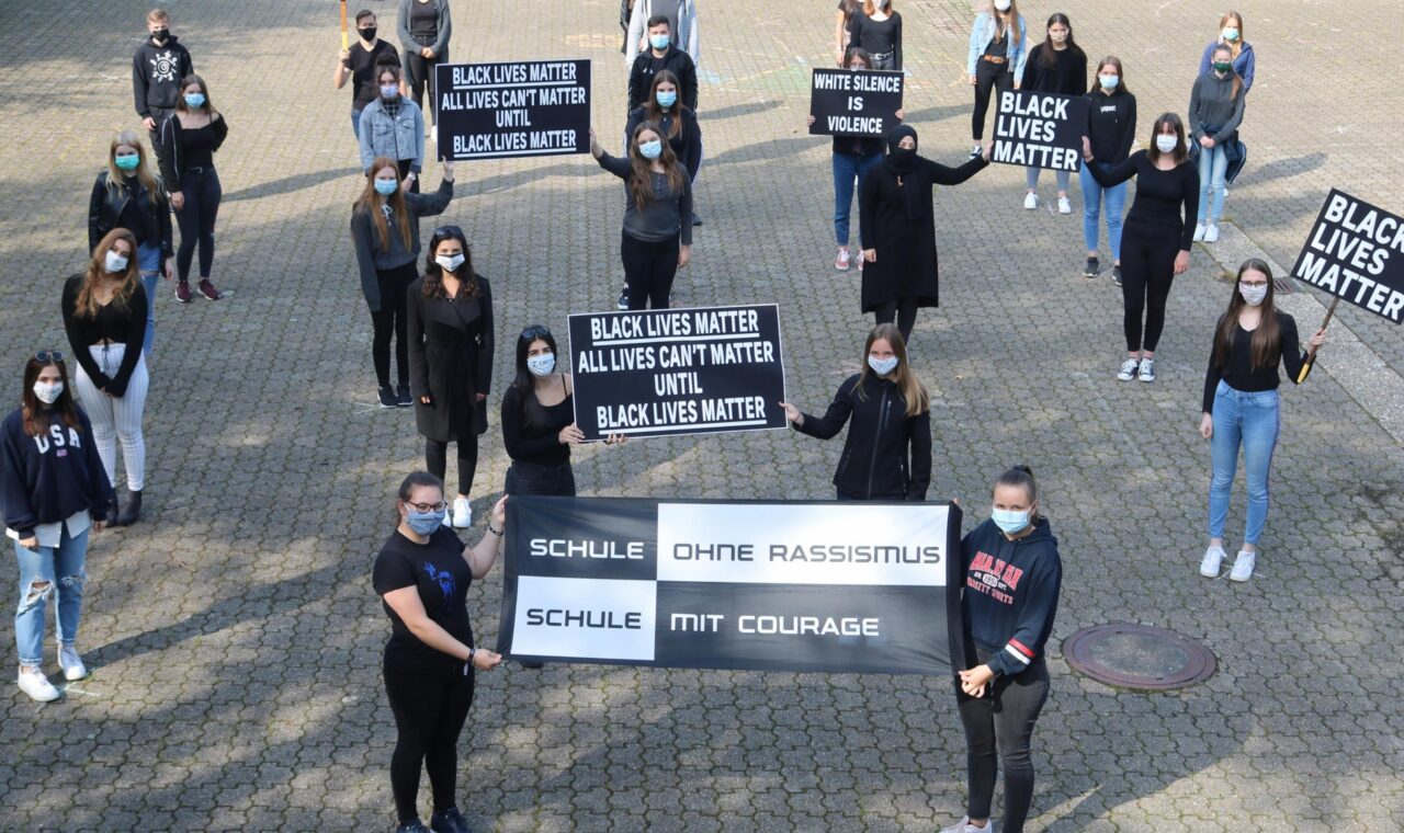 Schüler*innen halten Plakate für Black Lives Matter und gegen Rassismus.
