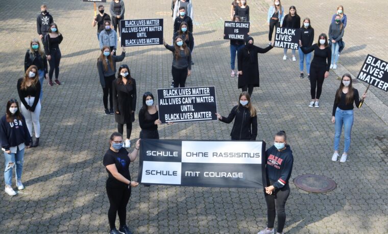 Schüler*innen halten Plakate für Black Lives Matter und gegen Rassismus.