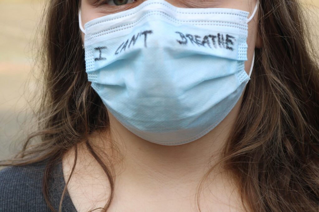 Mädchen mit Maske, auf der „I can't breathe“ geschrieben ist.