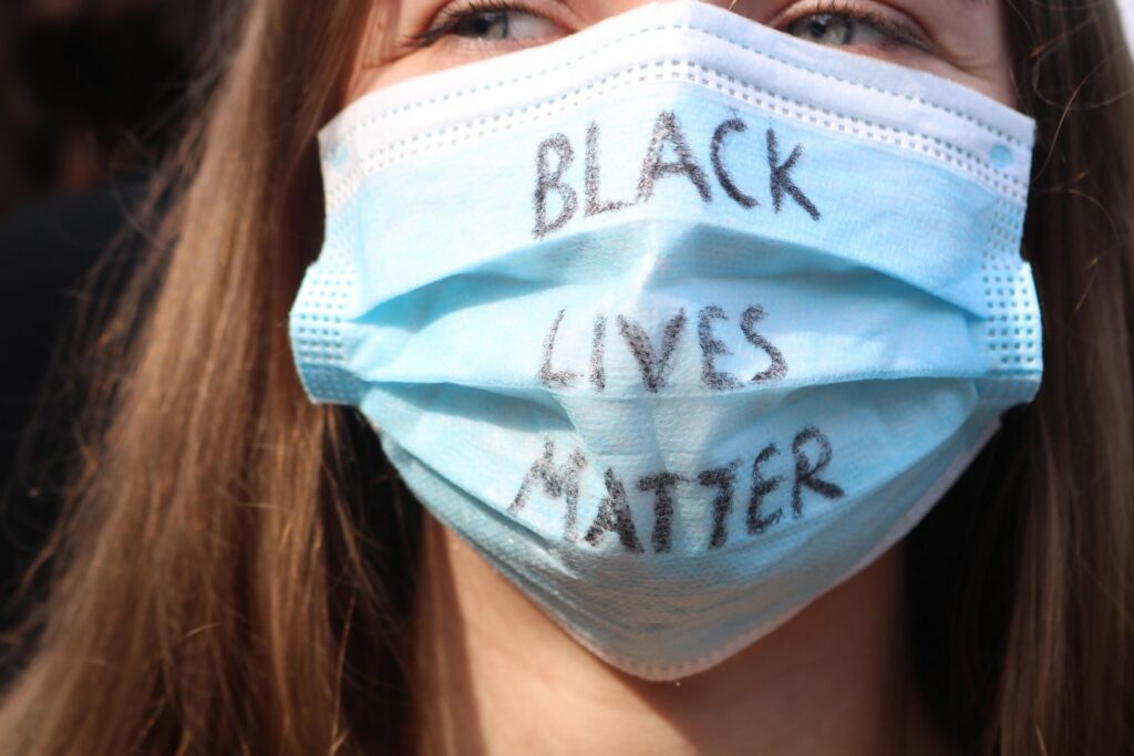 Person trägt einen Mundschutz mit der Aufschrift "BLACK LIVES MATTER".