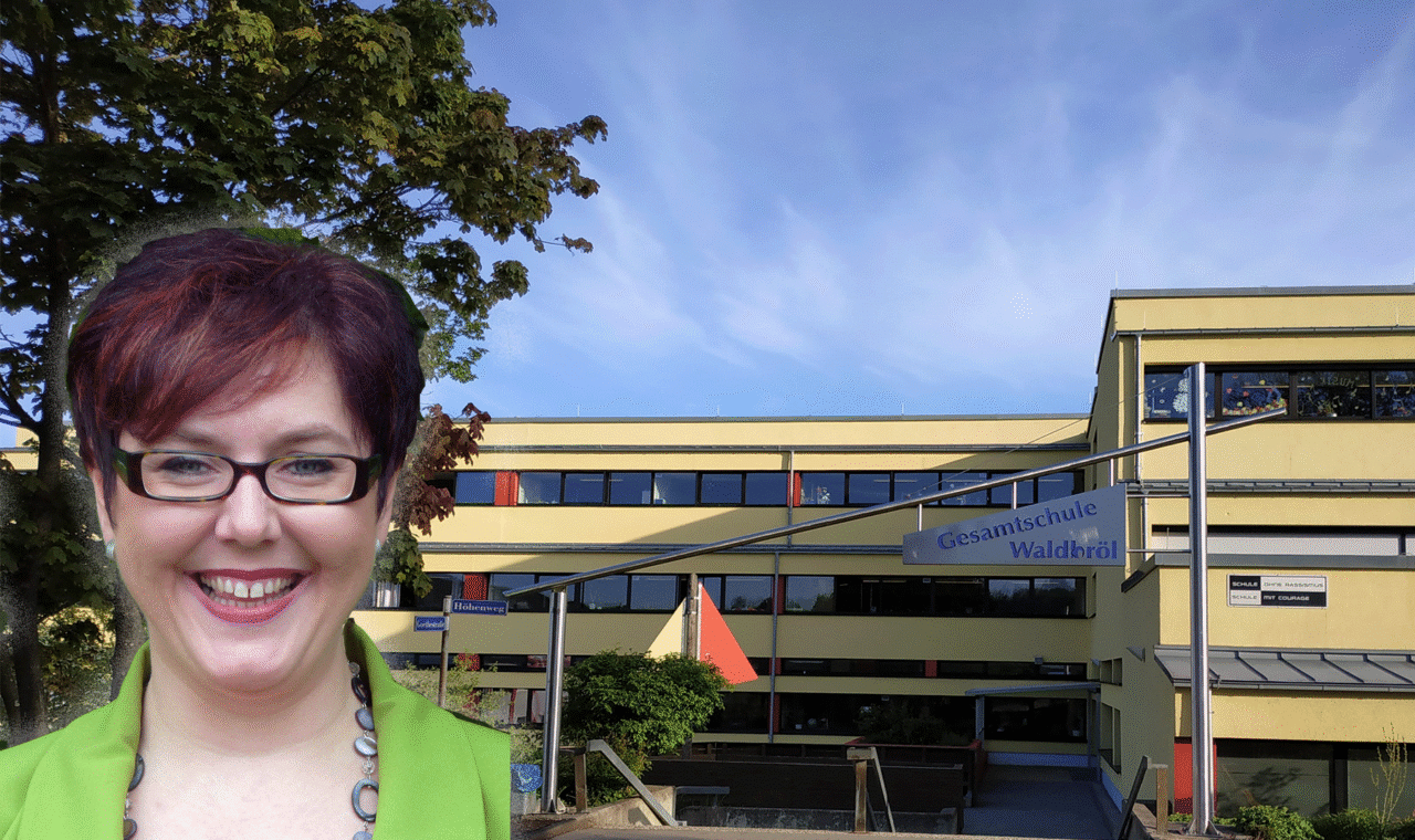 Schulgebäude mit einem lachenden Lehrer im Vordergrund.