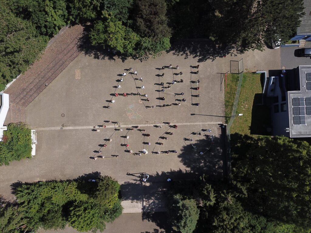 Schüler stehen auf einem Platz und bilden die Buchstaben "ABI 22".