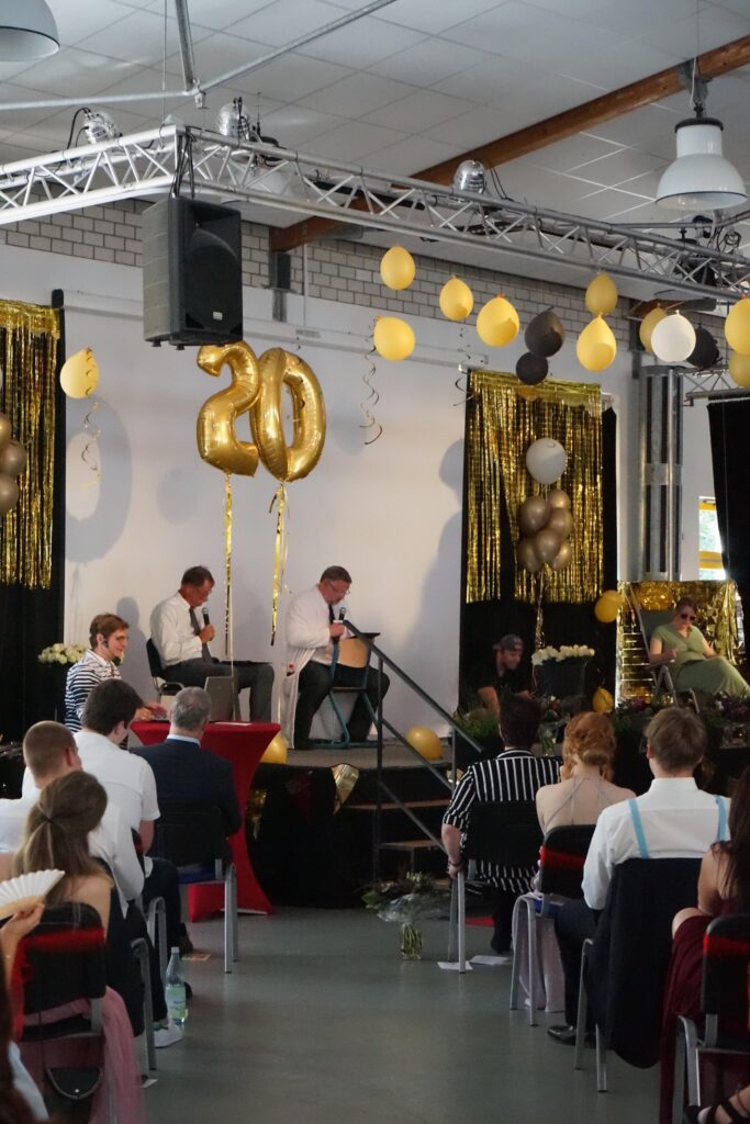 Feierliche Veranstaltung mit Bühne, Musikern und Dekoration in Schwarz und Gold.
