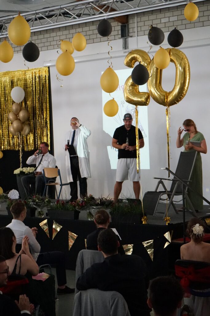 Feierliche Bühne mit goldenen und schwarzen Ballons, Dekoration und Rednern.