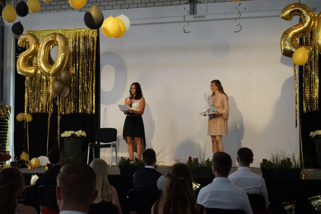 Zwei Frauen stehen auf einer Bühne mit Dekorationen und Luftballons.
