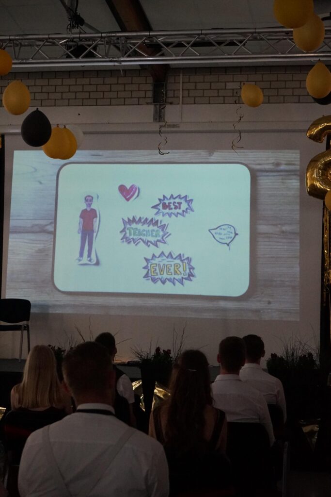 Präsentation mit Grafiken und einer Person im Vordergrund während einer Veranstaltung.