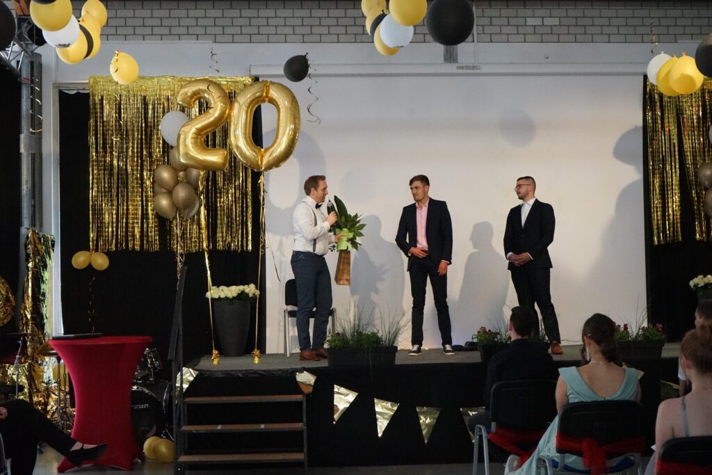 Feierliche Veranstaltung mit Rednern und dekorativer Kulisse zum 20-jährigen Jubiläum.