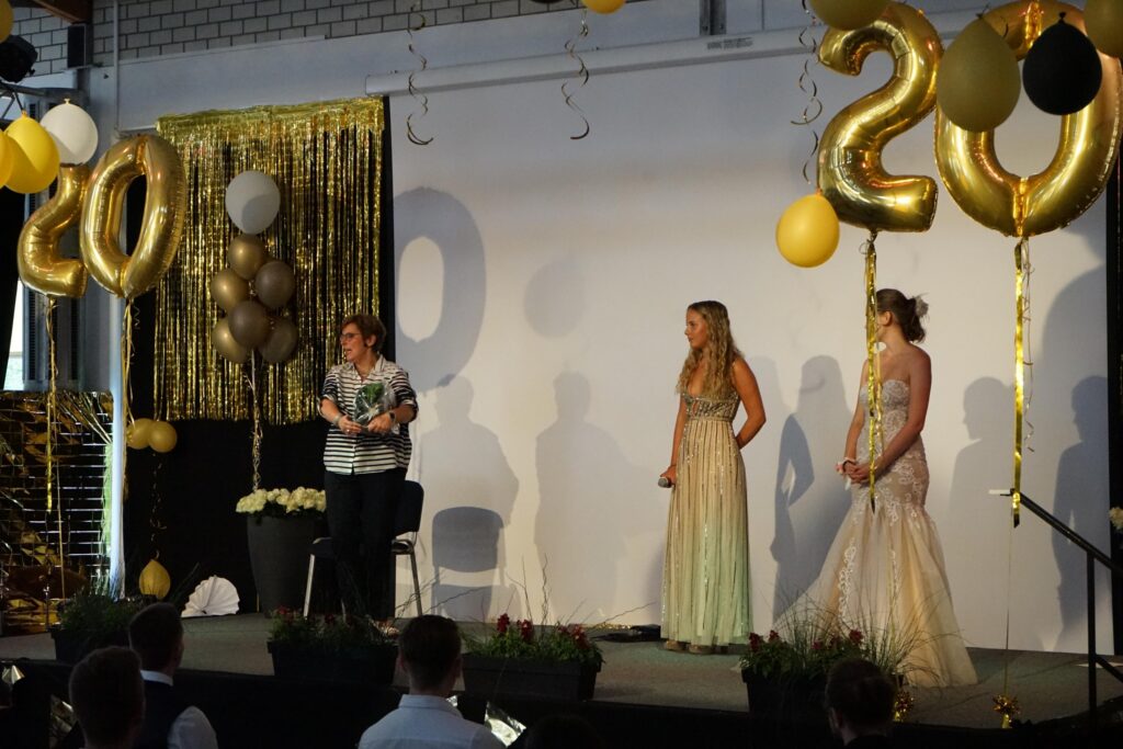 Zwei Frauen in eleganten Kleidern stehen auf einer Bühne mit 20er-Jahre-Dekoration.