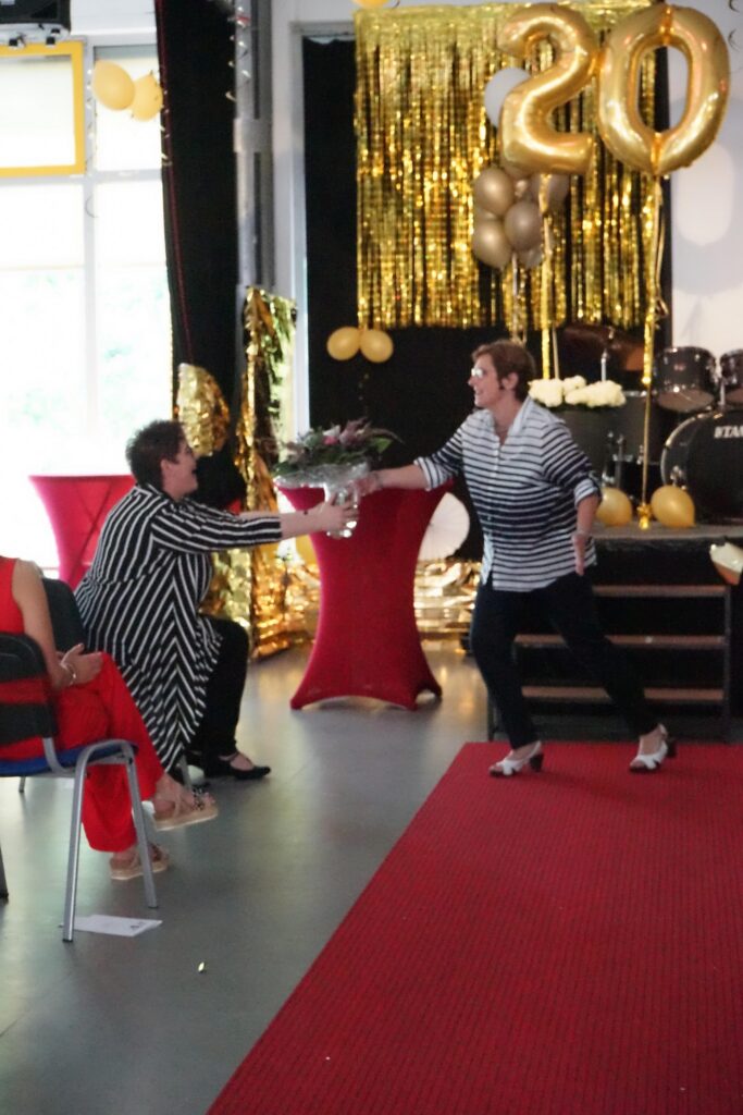 Zwei Frauen in gestreiften Outfits begrüßen sich auf einer festlichen Veranstaltung.
