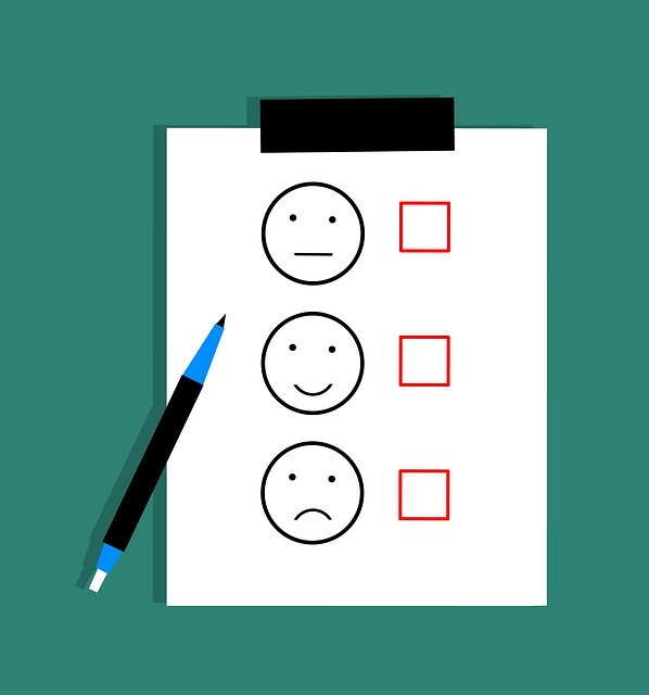 Umfragebogen mit Smileys und Kontrollkästchen, daneben ein blauer Stift.
