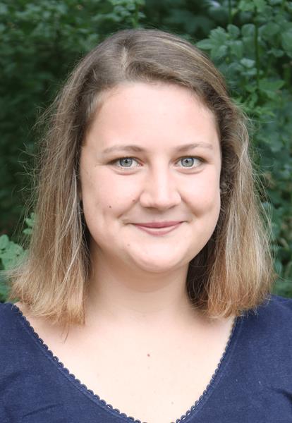 Porträt einer Frau mit blonden Haaren vor einer grünen Hintergrund.