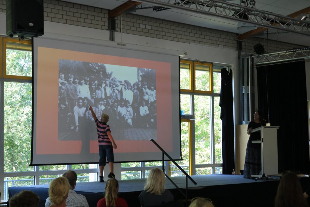 Schüler zeigt auf eine historische Fotografie auf der Projektionsleinwand.