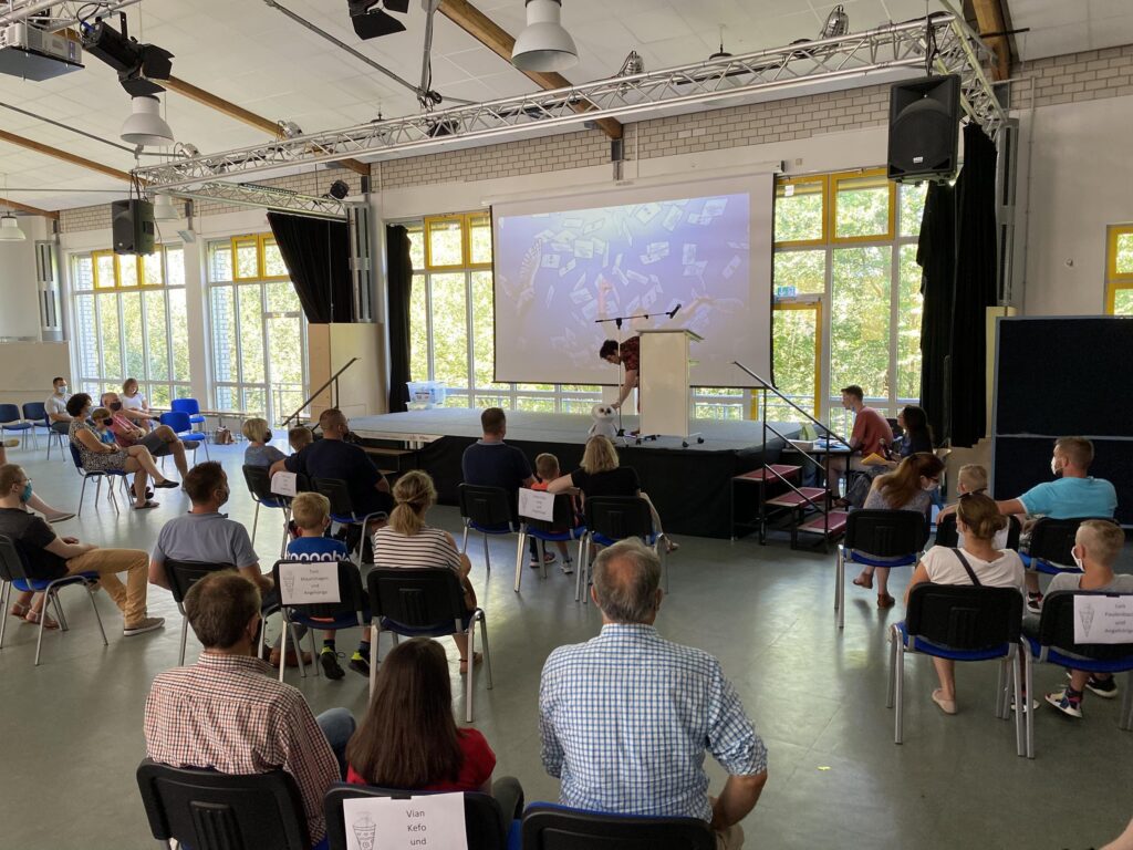 Veranstaltung im Schulraum mit Publikum vor einer Projektionsleinwand.