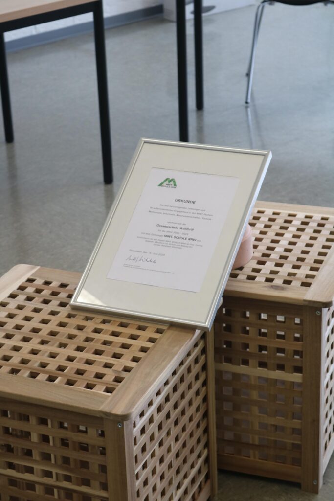 Urkunde in einem Rahmen auf zwei Holz-Kisten platziert.