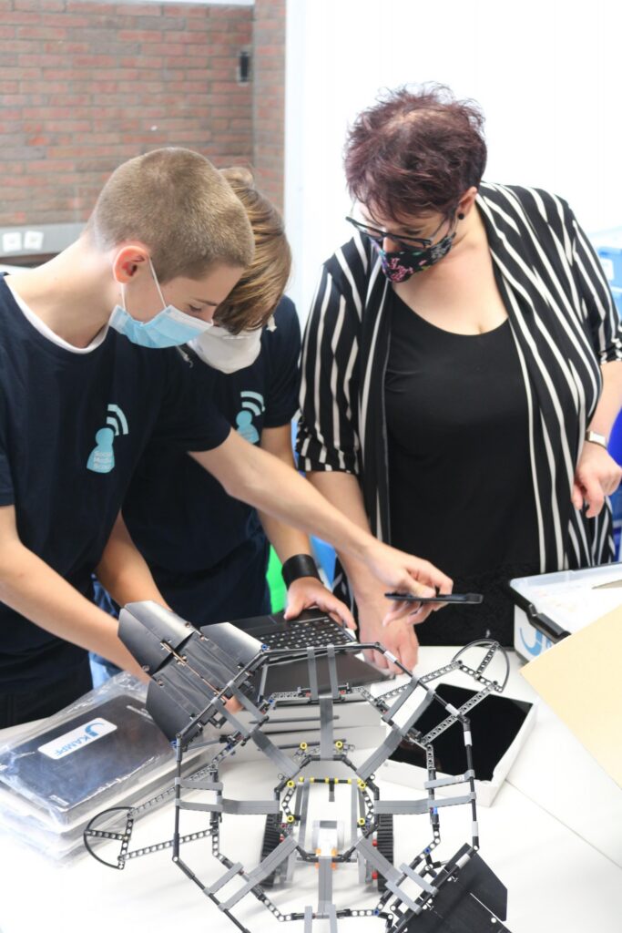 Schüler und Lehrerin arbeiten gemeinsam an einem Roboter-Projekt.