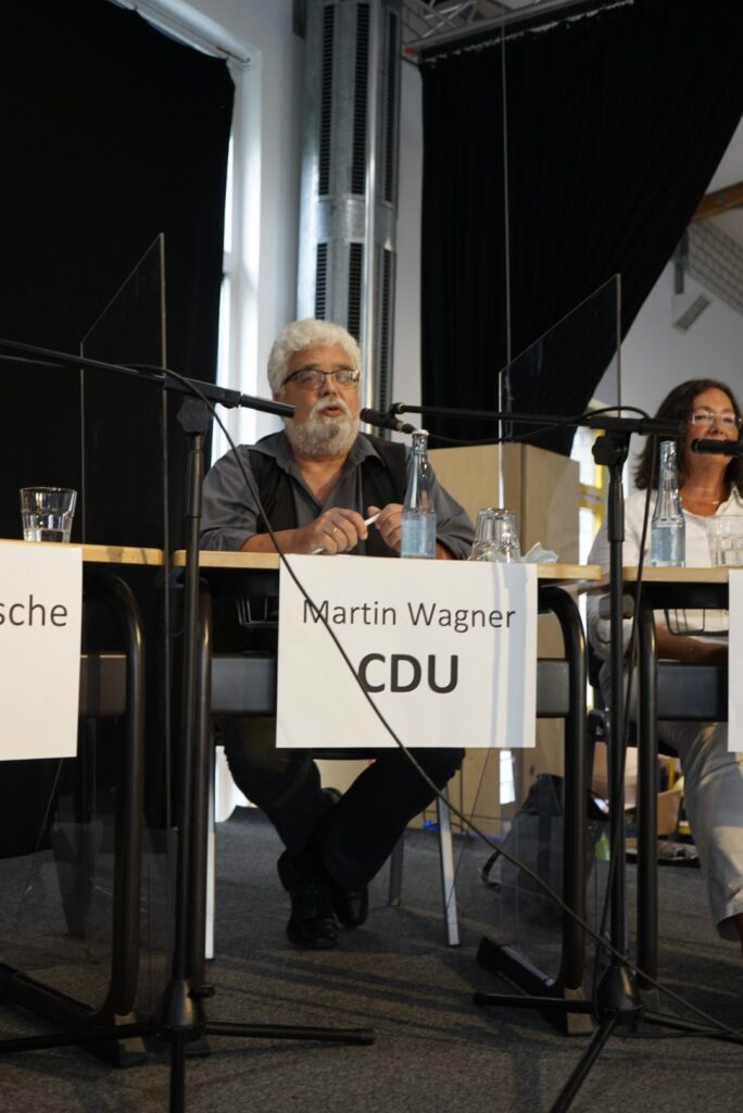 Diskussionstisch mit Rednern und Namensschildern, darunter Martin Wagner von der CDU.