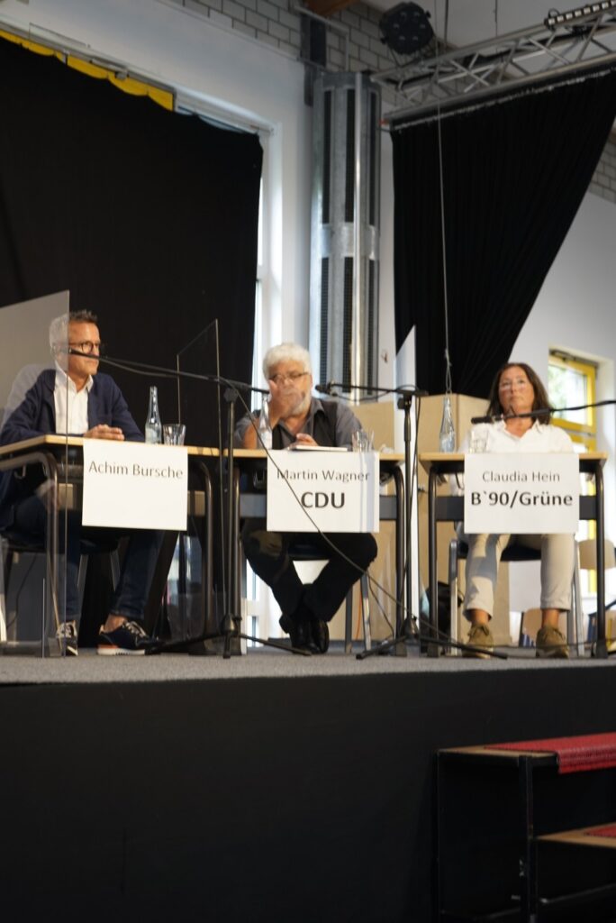 Podiumsdiskussion mit drei Rednern an einem Tisch.
