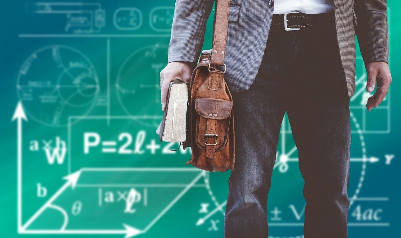 Lehrer mit Umhängetasche und Lehrbuch vor einer Tafel mit mathematischen Formeln.
