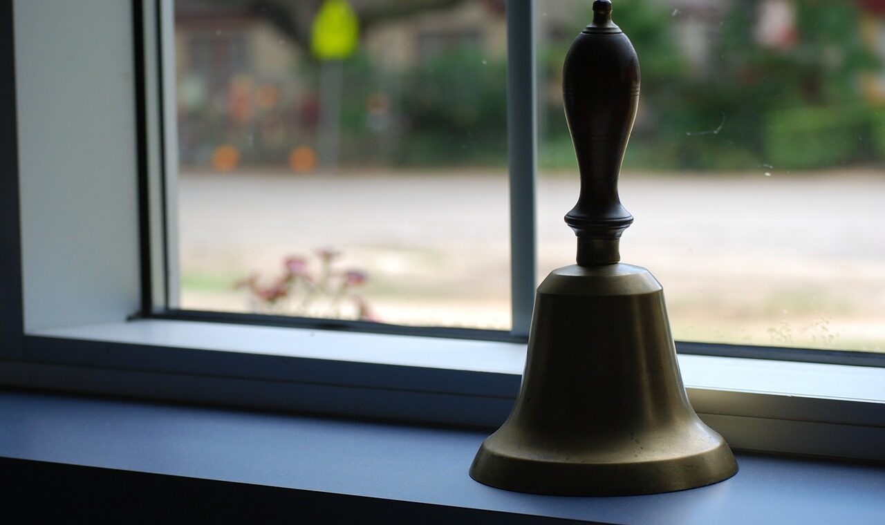 Eine goldene Glocke steht auf einer Fensterbank.