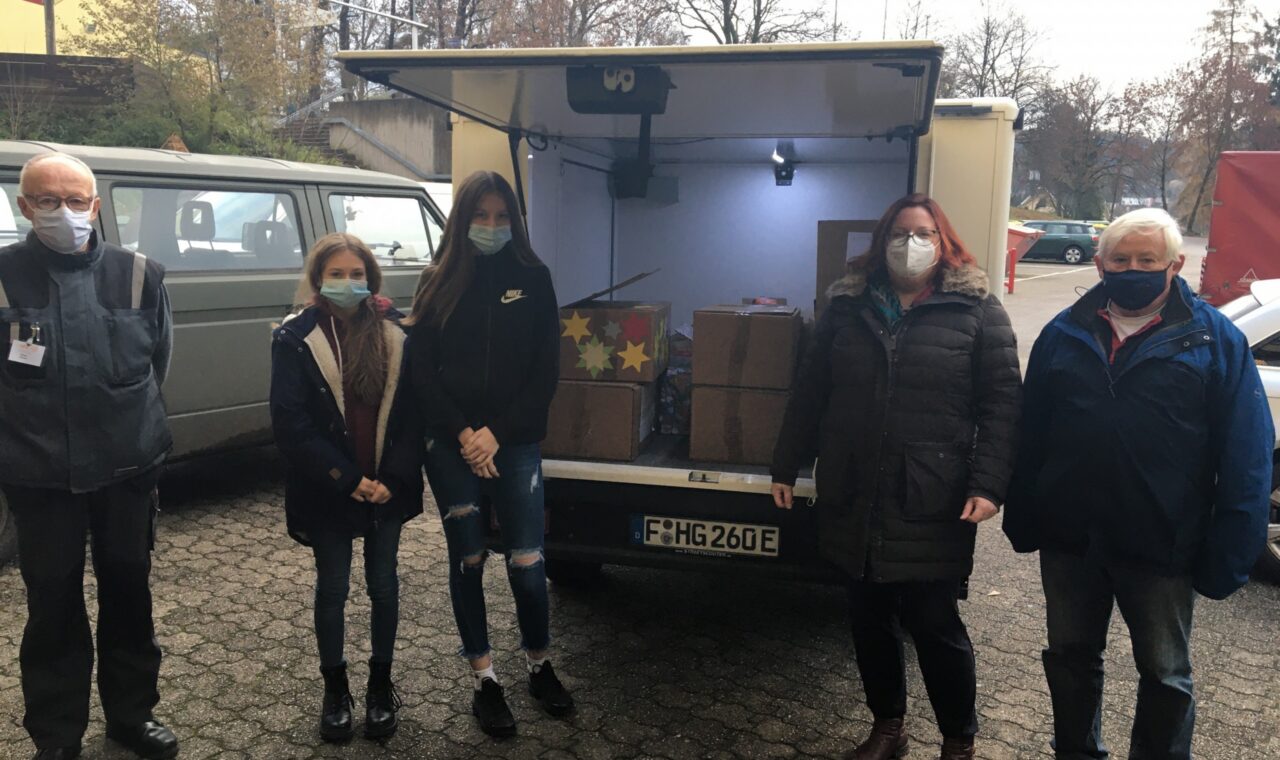 Fünf Personen stehen vor einem Lieferwagen mit Kartons im Inneren.