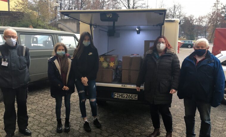 Fünf Personen stehen vor einem Lieferwagen mit Kartons im Inneren.