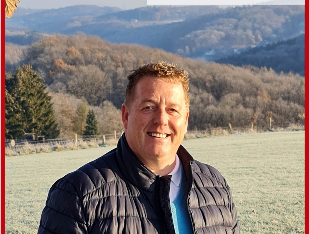 Mann steht in Landschaft, lächelt; Text über positive Erfahrung in der Schule.