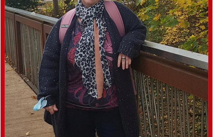 Frau steht auf einer Holzbrücke und lächelt in die Kamera.