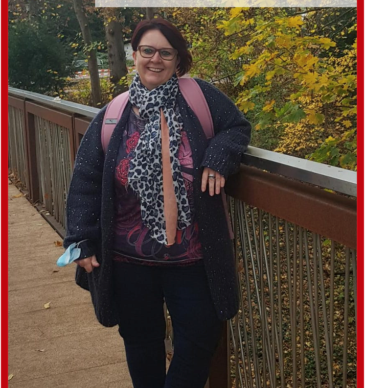 Frau steht auf einer Holzbrücke und lächelt in die Kamera.