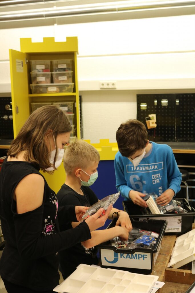 Schüler arbeiten an einem Tisch und sortieren Materialien in einer Werkstatt.