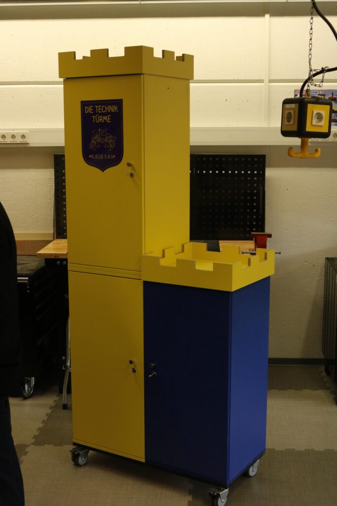 Ein gelb-blauer Schrank mit einem Türmchen, gestaltet wie eine Burg.