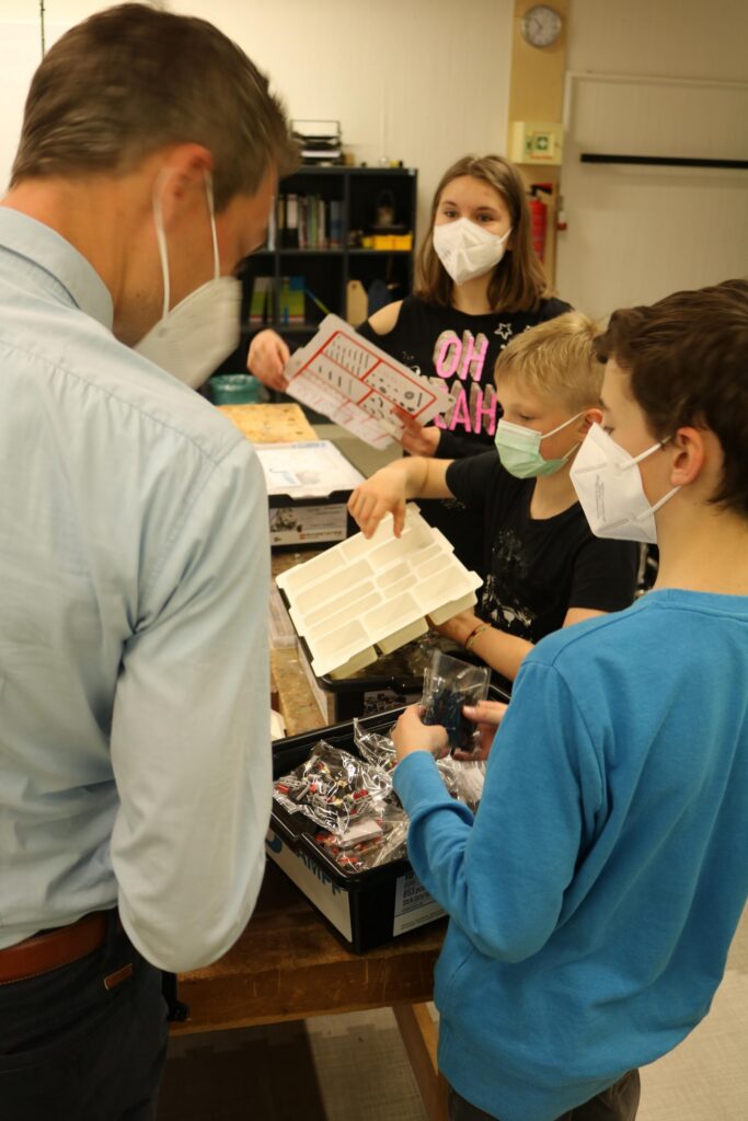 Lehrer und Schüler arbeiten gemeinsam an einem Experiment in einem Klassenraum.